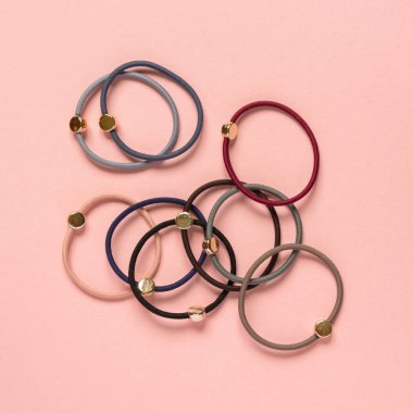 Pembe arka planda çok renkli saç bağları, üst görünümde.