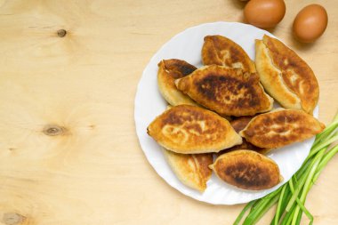 Yeşil soğanlı kızarmış turtalar ve beyaz tabakta yumurtalar.
