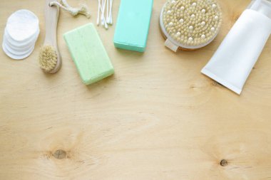 Düz banyo ve hijyen ürünleri. Sabun, şampuan ve masaj fırçaları ahşap arka planda, kopyalanmış alan