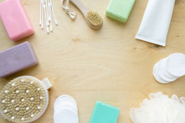 Banyo ve hijyen ürünleri çerçevesi. Sabun, şampuan ve masaj fırçaları ahşap arka planda, kopyalanmış alan