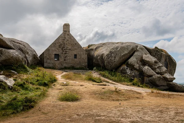 Kuzey Brittany 'deki Atlantik kıyısındaki Meneham' da kayaların arasındaki ev, yazın bulutlu bir gün.