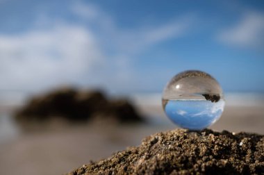 Yazın güneşli bir günde kumsalın kayasında uzanan cam küre.