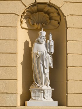 Aziz Leopold 'un beyaz taş heykeli güneşli bir günde Klosterneuburg Manastırı' nın sarı duvarına karşı bir kilise tutuyor.