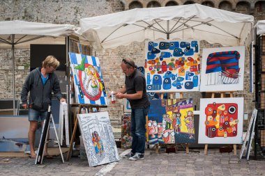 Saint-Malo, Fransa - 16 Ağustos 2018: Bir sanatçının sokak tezgahı bulutlu bir yaz gününde Saint-Malo Fransa 'da renkli resimler gösteriyor.