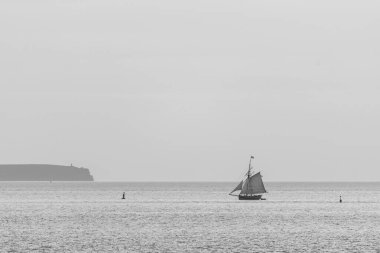 Günbatımında Saint Malo Fransa yakınlarında siyah-beyaz sanatsal bir kompozisyon içinde denizde yüzen bir tekne.