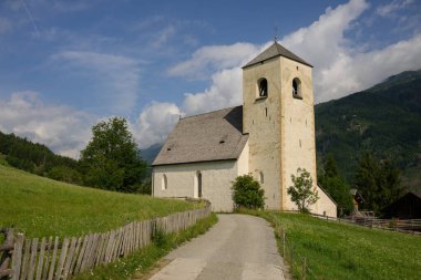 Matrei, Bichl yakınlarındaki Aziz Nikolaus Kilisesi güneşli yaz gününde yeşil çayır manzaralı.