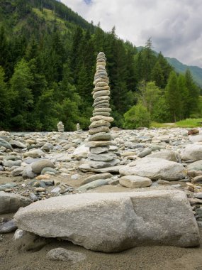 Praegraten Avusturya 'da, bulutlu bir yaz gününde, nehrin kenarında duran istiflenmiş taşlardan oluşan uzun bir kule huzurlu bir hava yaratıyor..