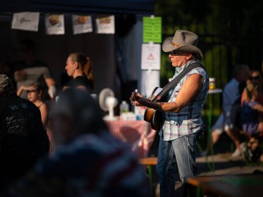 Viyana, Avusturya - 12 Eylül 2020: Jedleseer Kirtag Sonbahar Festivali 'nde gitar çalan ve şarkı söyleyen adam güneşli gökyüzü altında.
