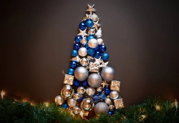Süslerden, toplardan, ışıklardan, posterlerden yapılmış mavi ve gümüş bir Noel ağacının çerçevesi.