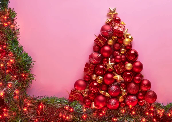 Süslerden, toplardan ve ışıklardan yapılmış kırmızı ve altın rengi bir Noel ağacı çerçevesi.