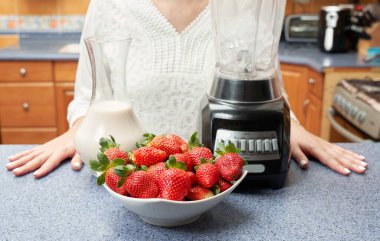 Badem sütü ve çilekten yapılmış sağlıklı bir smoothie yapmak üzere olan tanınmayan bir kadın.