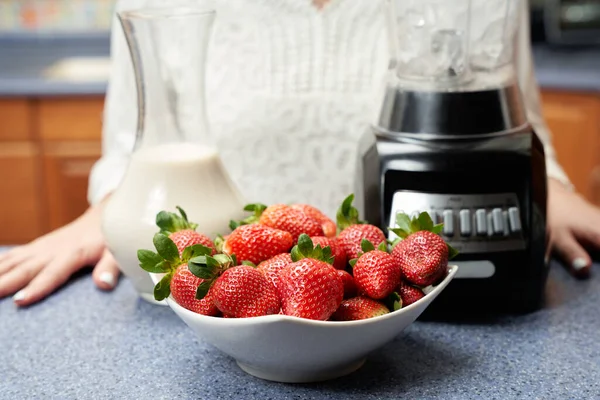 Badem sütü ve çilekten yapılmış sağlıklı bir smoothie yapmak üzere olan tanınmayan bir kadın.
