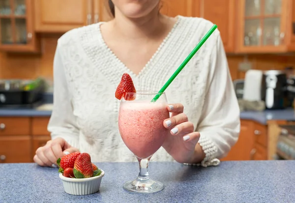 Badem sütü ve çilekten yapılmış sağlıklı bir smoothie içmek üzere olan tanınmamış bir kadın.