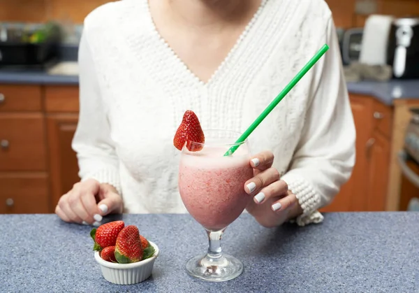 Badem sütü ve çilekten yapılmış sağlıklı bir smoothie içmek üzere olan tanınmamış bir kadın.