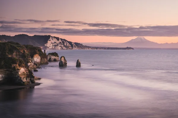 Zonsondergang over zee kust rotsen en mount Taranaki, Nieuw-Zeeland — Stockfoto