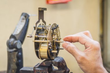 man fixing an old clock mechanism clipart