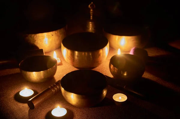 Sound healing music instruments for meditation, relaxation, yoga, massage, sound healing - tibetan singing bowls with candles on the dark background