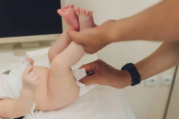 Mamma byter en liten nyfödd babys blöja som den ligger på rygg på ett skötbord i barnkammaren. baby hygien en en fuktig servett. — Stockfoto