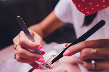 Cımbız içinde bir sürü yapay kirpik. Yapay kirpik eklentileri, yakın çekim. Güzellik salonunda bir kadın. Güzellik ve özgüven..