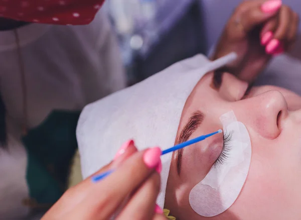 Bunch of artificial eyelashes in tweezers. Extensions of artificial eyelash, process close up. Woman in a beauty salon. Beauty and self-care. — Stock Photo, Image