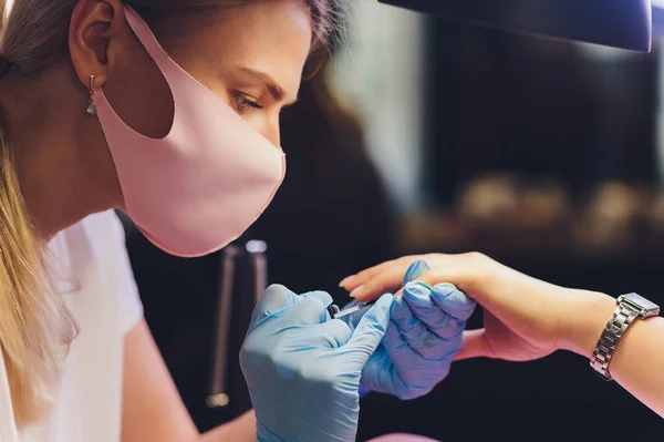 Close-up van schoonheidsspecialiste die kleurrijke vernis aanbrengt. Nagellak aanbrengen op nagels met een kwast voor het aanbrengen van nagellak op vingers. Manicure nagel applicator in een schoonheidssalon. In een schoonheidssalon vernis. — Stockfoto