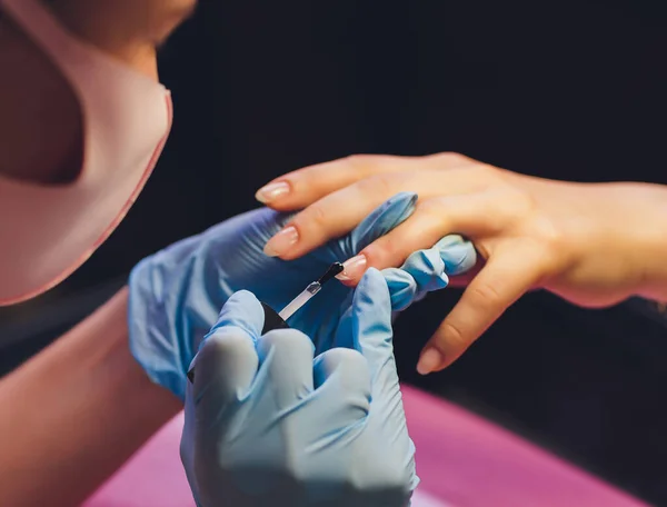 美容师应用彩色清漆的特写。用刷子把指甲油涂在指甲油上.美容院的指甲修补机在美容院里. — 图库照片