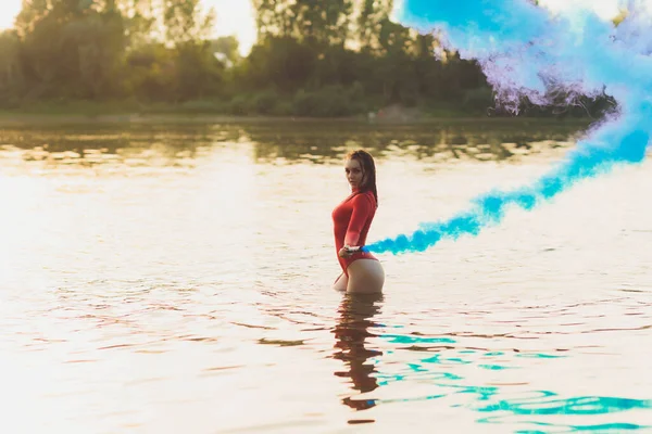 Mulher bonita em maiô vermelho posando perto do rio. Estilo de vida. bomba de fumo — Fotografia de Stock