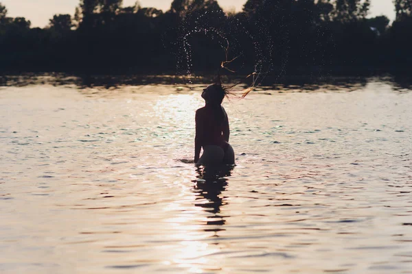 Bella giovane donna in costume da bagno rosso posa vicino al fiume. Stile di vita estivo. — Foto Stock