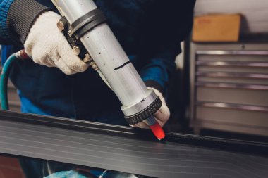 Camcı garajın ön camına lastik yapıştırıcı sürüyor..