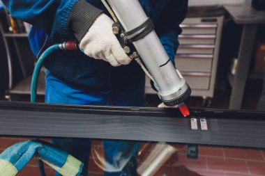 Camcı garajın ön camına lastik yapıştırıcı sürüyor..