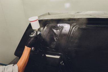 Boya kabininde araba boyayan bir işçi.,