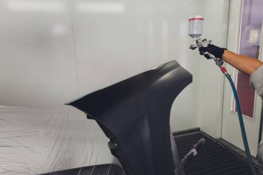 Boya kabininde araba boyayan bir işçi.,