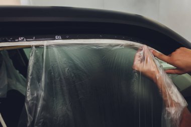 Tamirci kenarlarını koruyarak bir arabayı boyamaya hazırlıyor..