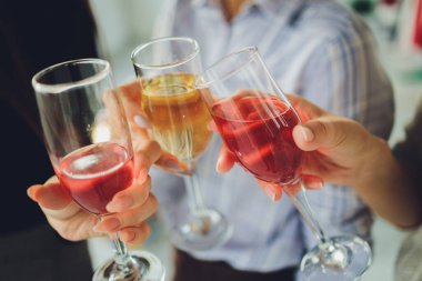 Bokeh arkaplanının önünde kadeh tokuşturup şampanya içen bir grup insanı yakından çek. Yaşlı insanların elleri.