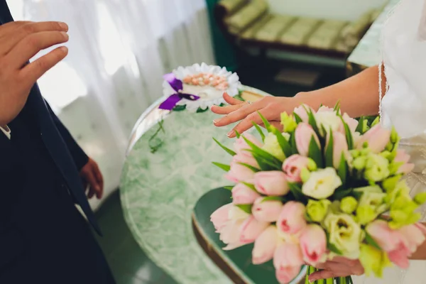 Nowożeńcy wymieniają obrączki, panna młoda wkłada obrączkę na ręce pana młodego w urzędzie stanu cywilnego. — Zdjęcie stockowe