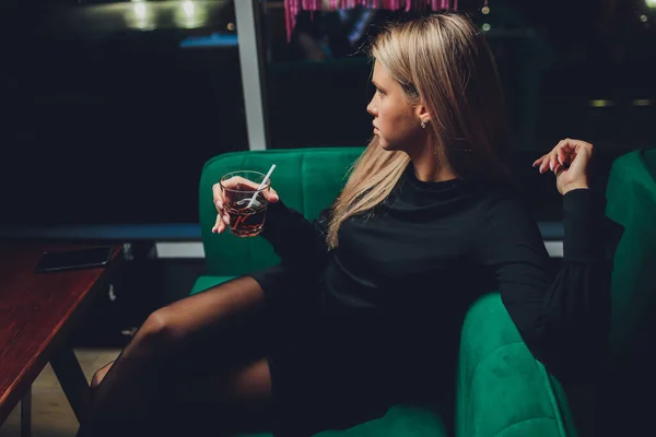 Счастливая женщина на вечеринке улыбается и держит коктейль. — стоковое фото