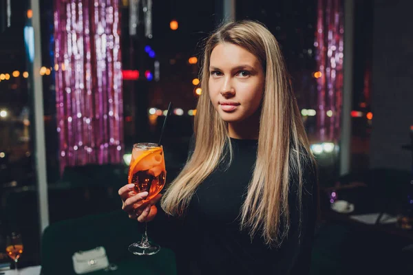 Щаслива жінка на вечірці посміхається і тримає коктейльний напій . — стокове фото