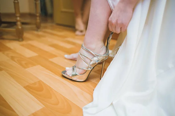 Panna młoda ubiera buty przed ślubem. Zarzuty wobec panny młodej. Zbliżenie szczegółów panny młodej zakładającej buty ślubne na wysokim obcasie. Ślubne panny młodej. Piękne nogi. — Zdjęcie stockowe