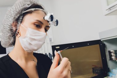 Büyüteç ve maske takan özel gözlüklü kadın dişçi. Sağlık çalışanı.