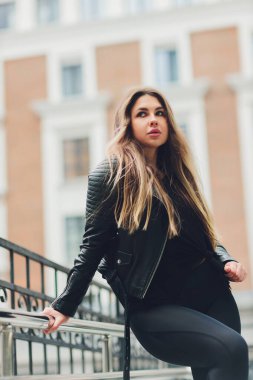 Geometrik bir kara evin arka planına karşı kentsel kıyafet giymiş güzel bir sarışın kız..