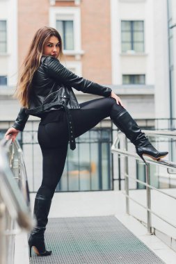 Geometrik bir kara evin arka planına karşı kentsel kıyafet giymiş güzel bir sarışın kız..