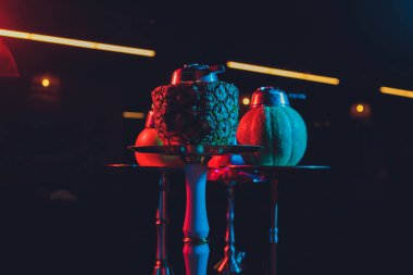 Duman ve ahşap masa tuğlasında kırmızı kıvılcımlar olan kırmızı shisha nargilesi, sanat arka planı. Shisha Kavramı.