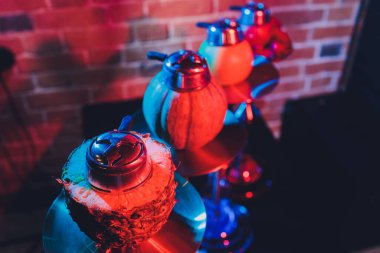 Duman ve ahşap masa tuğlasında kırmızı kıvılcımlar olan kırmızı shisha nargilesi, sanat arka planı. Shisha Kavramı.
