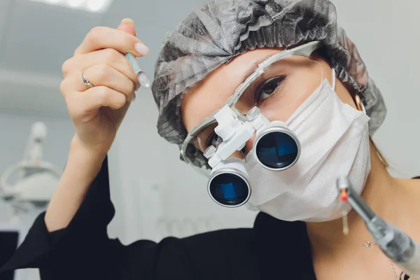 Büyüteç ve maske takan özel gözlüklü kadın dişçi. Sağlık çalışanı. — Stok fotoğraf