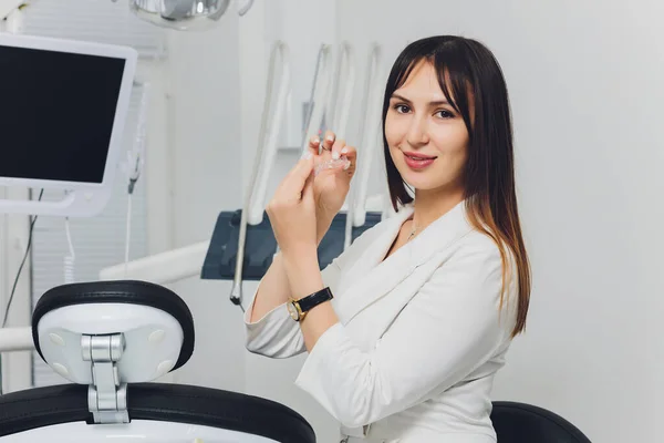 Retrato de una atractiva dentista sonriente con las manos dobladas. —  Fotos de Stock