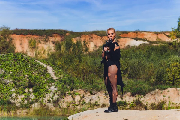 Beautiful woman soldier holding a rifle standing on a rock on the mountain.blue sky hot sun. — Stock Photo, Image