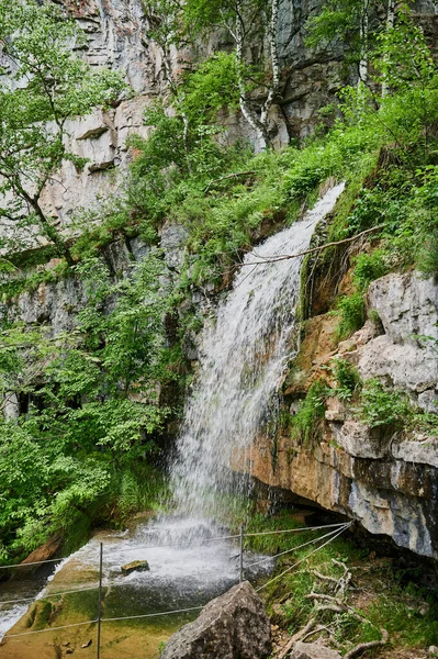 Zicht op een kleine berg rivier waterval tussen grote kasseien van een klif. — Stockfoto