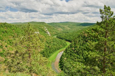 Öndeki yeşil tarlaların doğal görüntüsü ve güneşli bir yaz gününde arka plandaki uçurum ve tepelerin dağları..