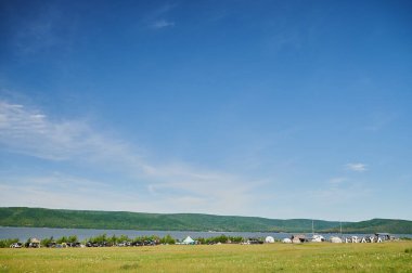 Öndeki yeşil tarlaların doğal görüntüsü ve güneşli bir yaz gününde arka plandaki uçurum ve tepelerin dağları..