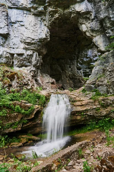 view of a small mountain river waterfall among large cobblestones from a cliff.